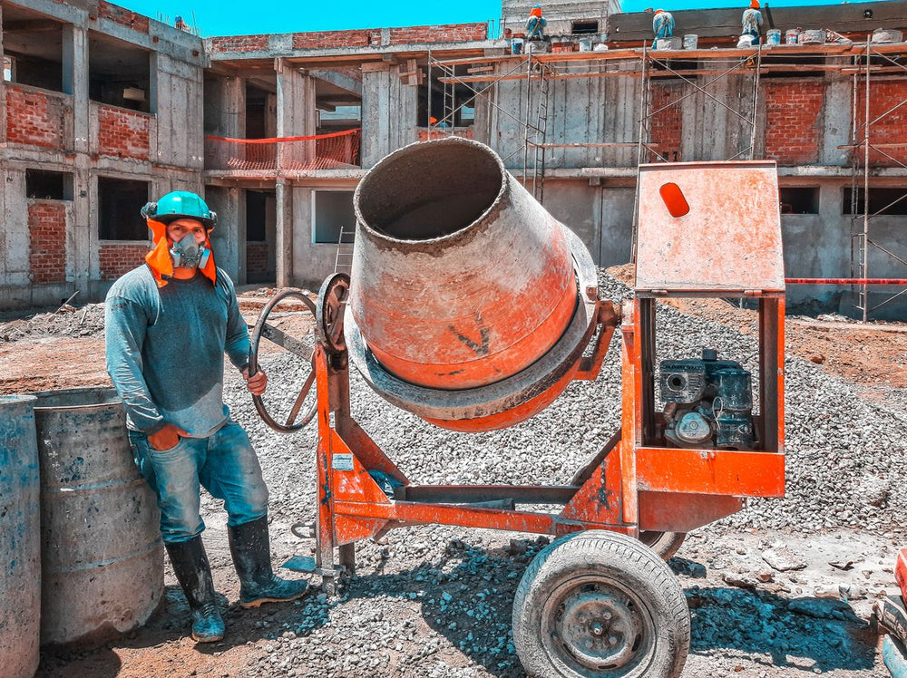 Worker operating a portable concrete mixer on a job site